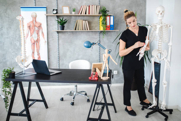 istock Cheerful female teacher leading an anatomy class on plastic skeleton 1203234094