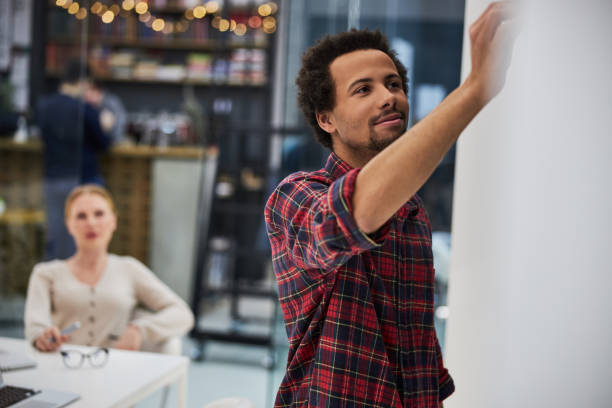 istock Handsome afro american man writing on chalkboard 1203236324