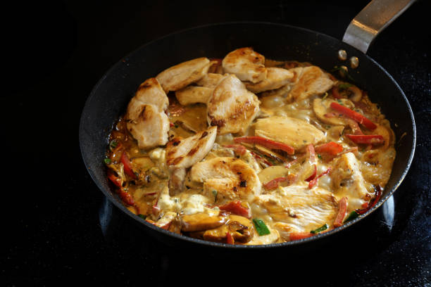 cucinare un ragù di pollo cremoso con peperone e fungo in una padella su una stufa nera, copiare lo spazio - pepper bell pepper portion vegetable foto e immagini stock
