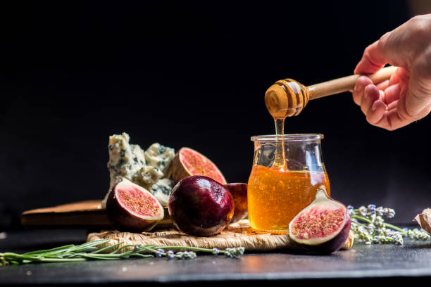 istock honey, figs and cheese on a wicker plate. Black background 1203237670