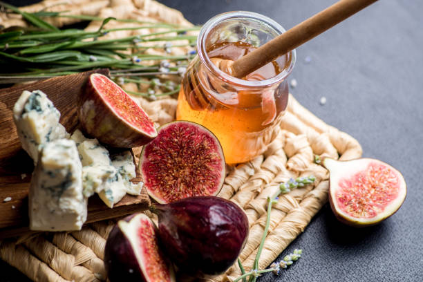 istock honey, figs and cheese on a wicker plate. Black background 1203237673