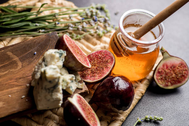 istock honey, figs and cheese on a wicker plate. Black background 1203237680
