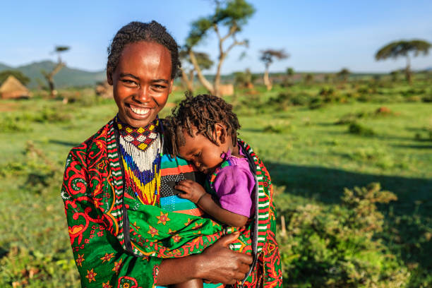femme de la tribu borana retenant son bébé, ethiopie, afrique - africa child village smiling photos et images de collection