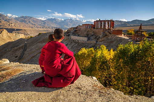Novice Tibetan buddhist monks looking at the view in Tsarang village in Upper Mustang. Tsarang monastery on the background. Mustang region is the former Kingdom of Lo and now part of Nepal,  in the north-central part of that country, bordering the People's Republic of China on the Tibetan plateau between the Nepalese provinces of Dolpo and Manang.