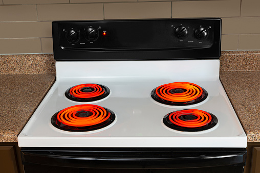 Horizontal shot of the stovetop of an electric range with all the burners turned to high and glowing red.