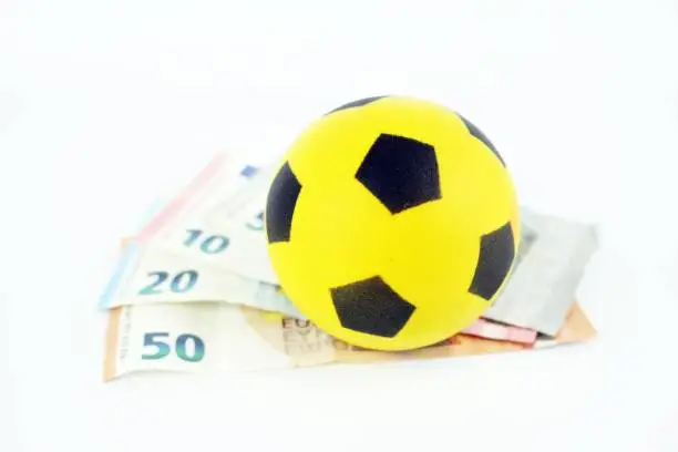 Interests of football and betting. Small sponge ball on top of euro banknotes.