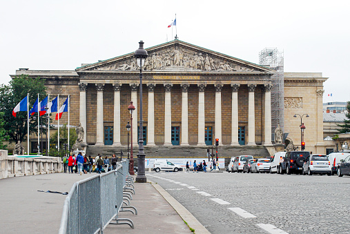 Paris, France; 07/10/2014: National assembly building in Paris, France with several French flags on the bridge