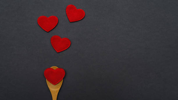 istock Wooden spoon with hearts on a black background. 1203249513