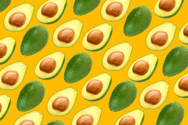 istock Avocado pattern background with halves and whole avocados 1203249971