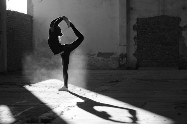 Silhouette of ballerina dancing in abandoned building Silhouette of ballerina dancing in an abandoned building on a sunny day in black and white. ballerina shadow stock pictures, royalty-free photos & images