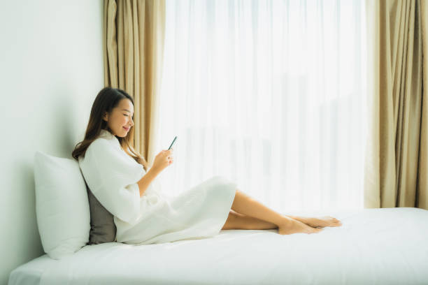 istock Young asian woman using mobile smart phone on bed 1203258457