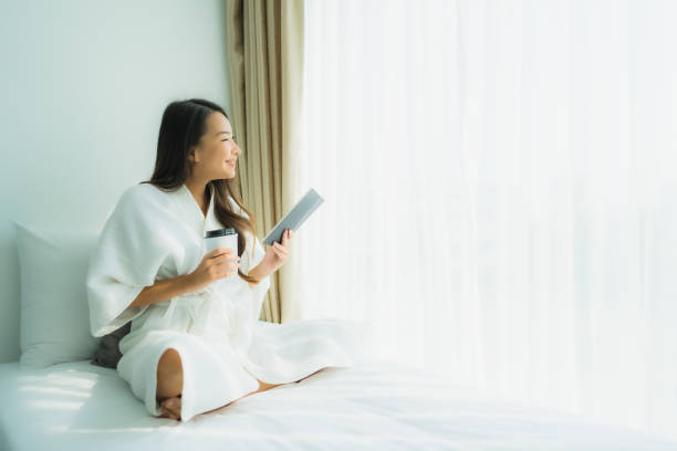 istock Young asian woman with coffee cup and read book 1203259288
