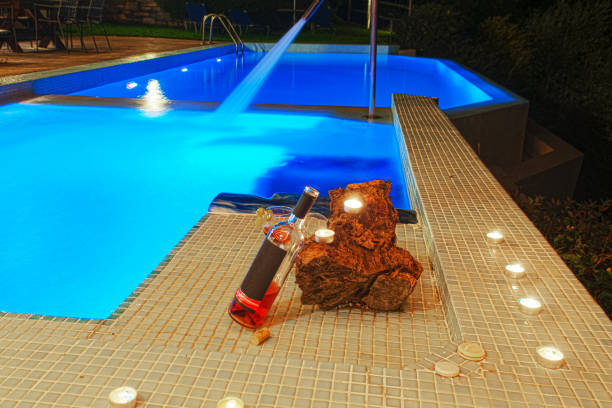 istock two glasses and bottle of wine at poolside, romance mood 1203259364