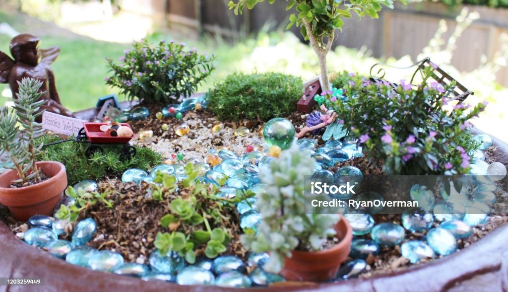 Fairy Garden in a large bird bath with blue rocks and miniature plants Fairy Costume Stock Photo