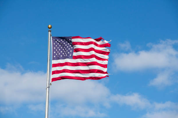 istock American flag with blue sky background 1203261774