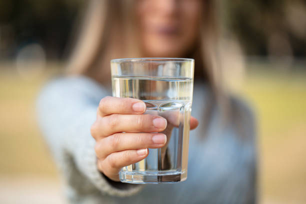 健康な生活のためにコップ一杯の水を伸ばす女性 - water women glass healthy eating ストックフォトと画像