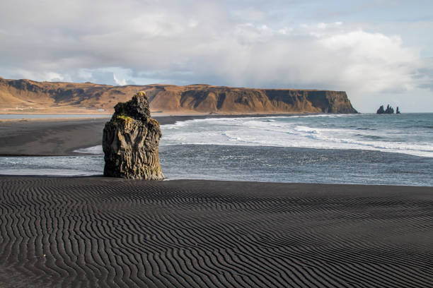 istock Rocks in the sea on a black sand beach 1203263337