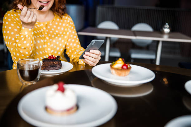 istock Smiling lady eating cake and using smartphone 1203264508