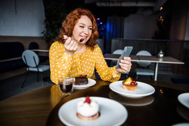istock Charming lady eating cake and using cellphone in cafe 1203264524
