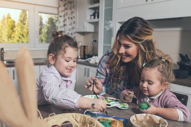 istock A mother and her two daughters preparing Easter eggs in their kitchen. They are painting the eggs with watercolors. 1203266214
