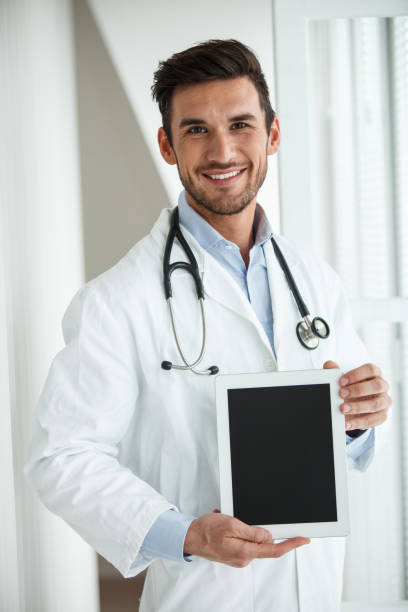 istock Successful male doctor holding digital tablet and looking at camera 1203266955