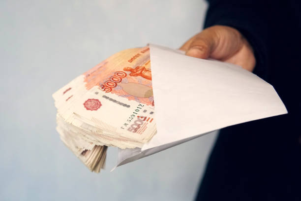 istock Large denominations of 5000 rubles in a white envelope. man hand holds an envelope with money. the concept of bribery and corruption. cash, cashflow 1203266977