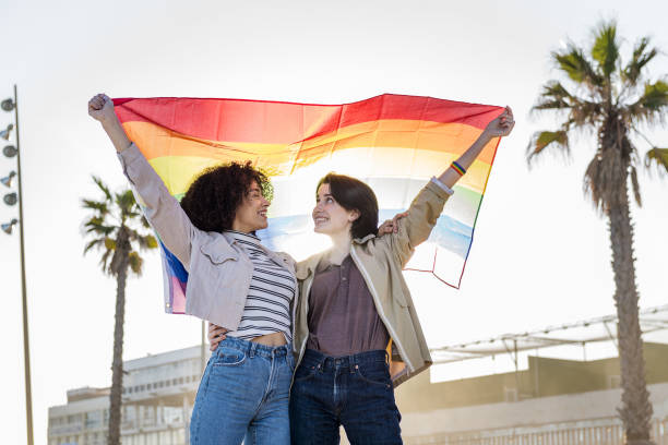 istock young lesbian couple smiling under a rainbow flag 1203267425
