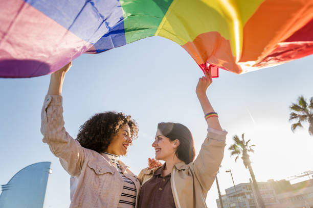 istock smiling young lesbian couple waves a rainbow flag 1203267430