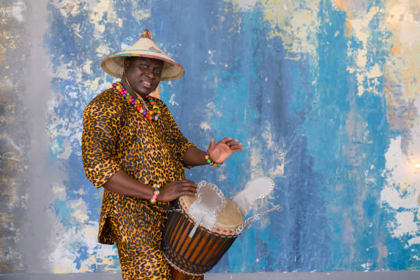 Handsome african drummer weared in traditional costume playing on djembe drum.