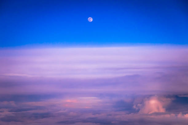A beautifully illuminated crescent moon shines through soft clouds, creating a tranquil atmosphere in the night sky, enhancing the tranquility of the evening.