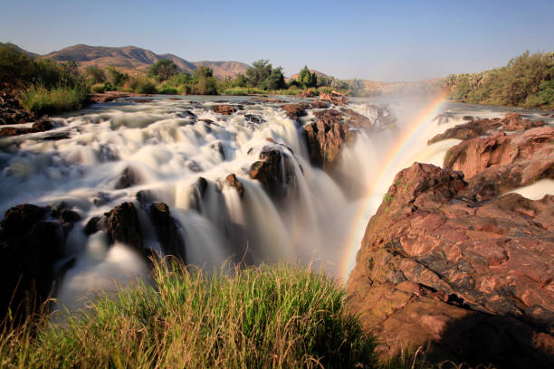 Gushing Epupa Falls separating Namibia and Angola. A very rare phenomenon captured in a long exposure. Gushing Epupa Falls separating Namibia and Angola. A very rare phenomenon captured in a long exposure. Around the world solo travel concept image. kaokoveld stock pictures, royalty-free photos & images