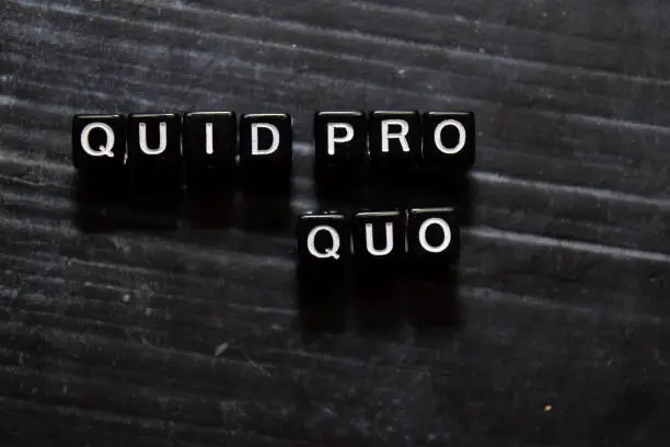 Photo of Quid Pro Quo in Latin on wooden cubes. On table background