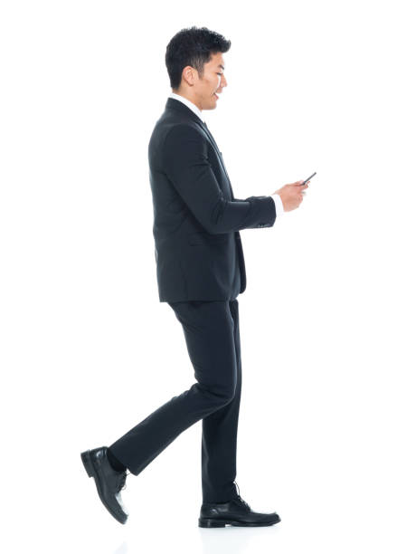 istock Young male business person walking and using mobile phone 1203293675