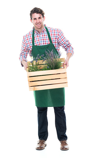Full length of aged 20-29 years old caucasian young male with part-time job crouching wearing apron who is happy who is punching and holding plant