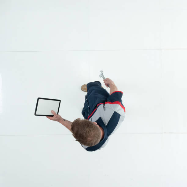 Caucasian young male technician walking wearing uniform and holding work tool and using touch screen Aerial view of aged 20-29 years old caucasian young male technician walking wearing uniform and holding work tool and using touch screen car mechanic top view stock pictures, royalty-free photos & images