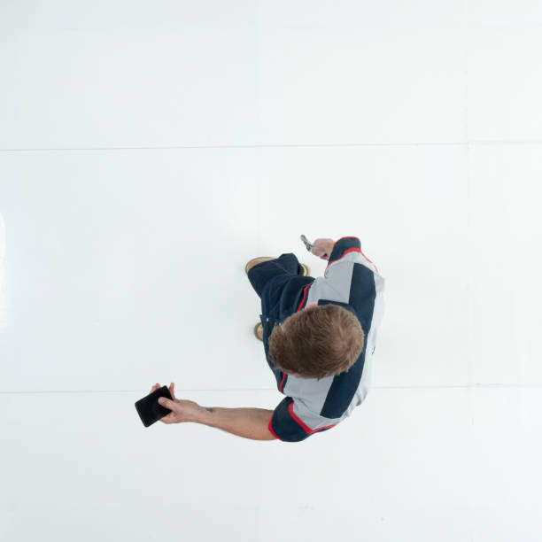 istock Caucasian young male technician standing wearing uniform and holding wrench and using smart phone 1203304490