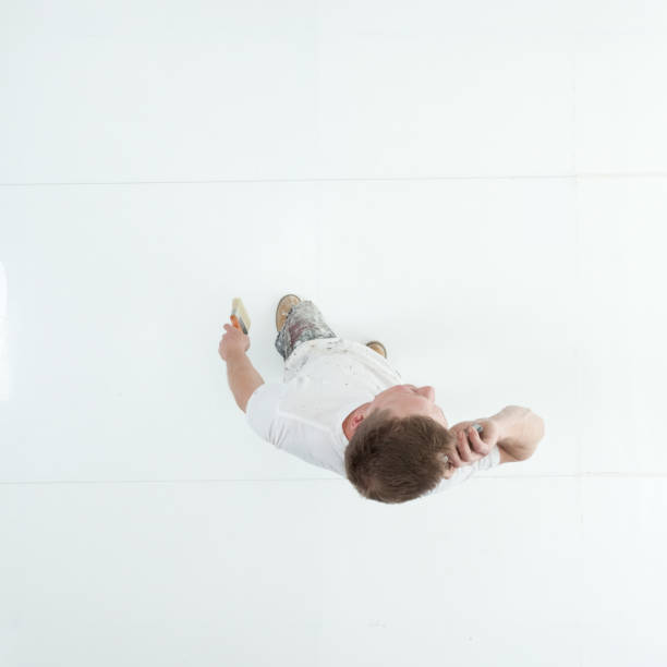 istock Caucasian young male painter standing wearing uniform and holding paintbrush and using smart phone 1203304517