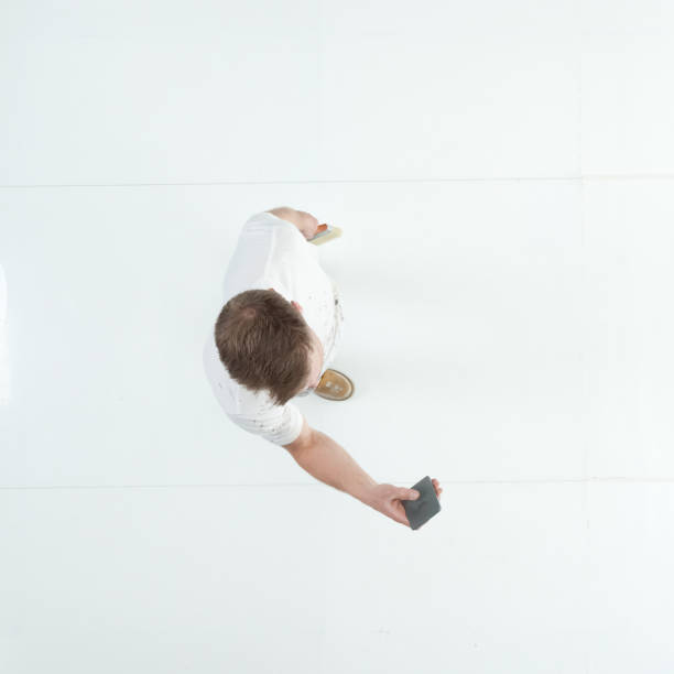 istock Caucasian male house painter standing wearing uniform and holding paintbrush and using mobile phone 1203304582