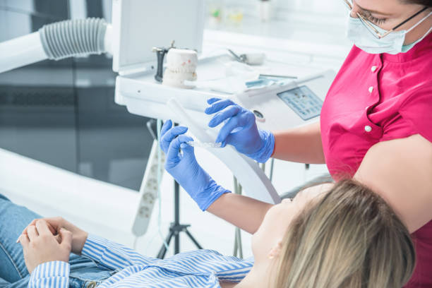 ärztin hält zahnmundschutz in den händen, schienentherapie in der zahnmedizin, um biss zu korrigieren - dentists chair dentist office chair orthodontist stock-fotos und bilder