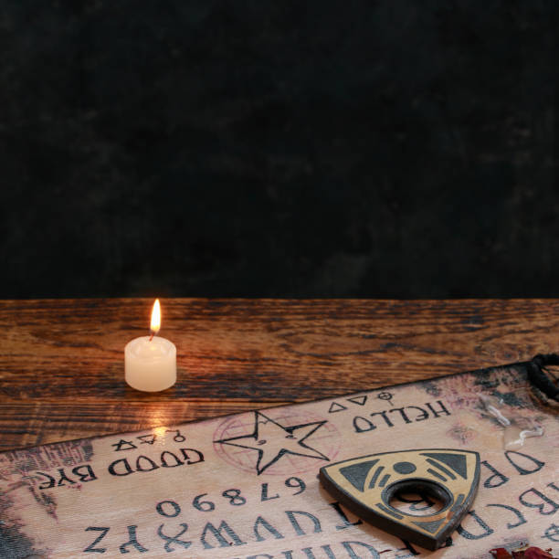 istock Mystic ritual with Ouija and candles. Devil's board concept, black magic or fortune telling rite with occult and esoteric symbols. 1203309854
