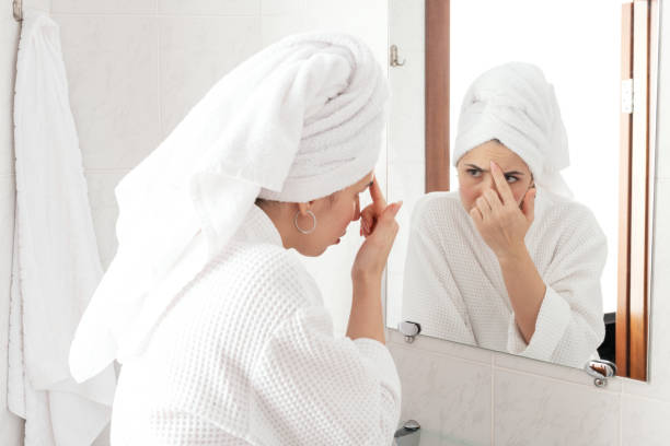 istock Beautiful middle-aged brunette looking at mirror and touching wrinckles on her forehead. Anti aging treatment prevention cream using 1203312231