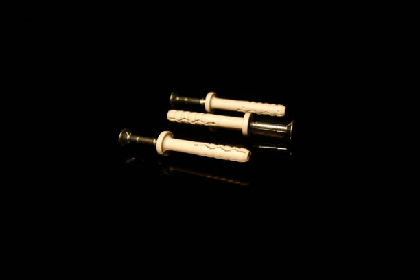 istock Three wall dowel pin with screw isolated on black with reflections 1203314107