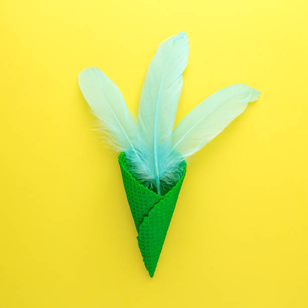 istock Green ice cream cone with pastel blue feathers food abstract. 1203321099