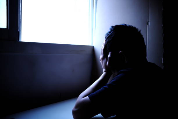 Sillhouette of a sad and problematic young man sitting next to a window light source. Mental health concept Sillhouette of a sad and problematic young man sitting next to a window light source. Mental health, depression and stress concept silhouette of bad boy stock pictures, royalty-free photos & images