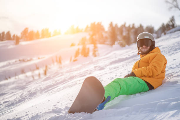 istock smiling snowboarder sitting on the mountain slope on the sunset. 1203324537