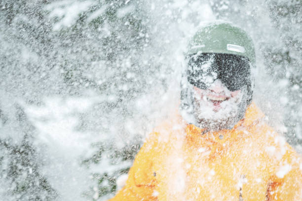 スキーヤーの肖像画。森の雪吹雪の中、ヘルメットと黒いゴーグルを着たひげを生やした男。彼の顔に雪と幸せと笑顔のスノーボーダー。 - sports helmet powder snow ski goggles skiing ストックフォトと画像