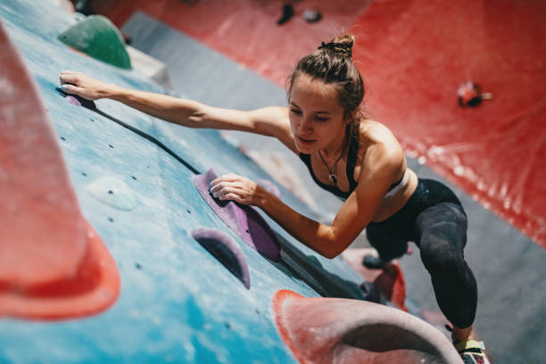 istock Muscular woman on boulder climbing training, reaching the top 1203324696