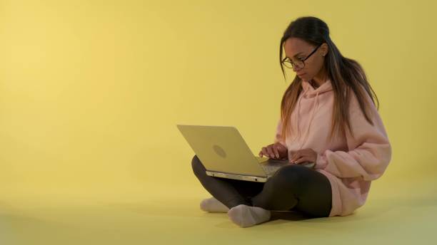 istock Smart african girl working on the computer on yellow background 1203327034