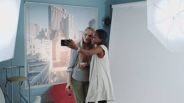 istock Famous black model making selfie with make-up artist while she applying makeup 1203329976