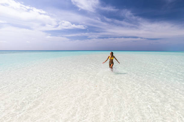 istock Young happy woman having fun while running through sea. 1203329999